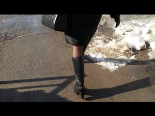 a woman in tights and boots goes to a bus stop